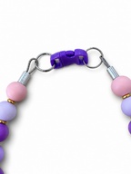 Close-up of the Pink Pawsch beaded dog necklace showing the purple clasp, silver rings, cable, crimps, and pink and purple beads on a white background